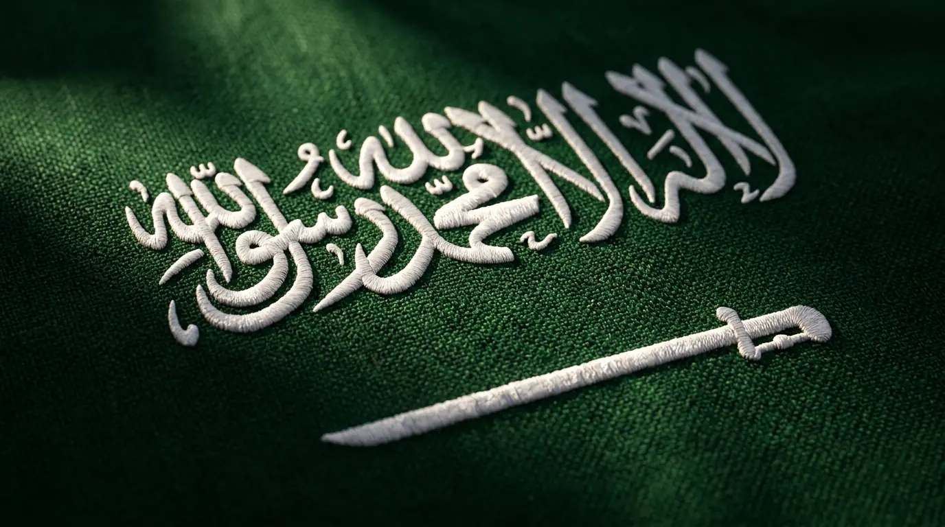 Close-up of Saudi Arabia flag showing Shahada calligraphy in Thuluth script and sword emblem on green fabric